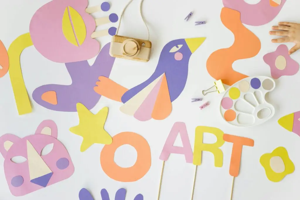 Vibrant flatlay of colorful paper cutouts and art tools, perfect for creative educational projects.